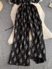 Black patterned jumpsuit with drawstring waist and wide legs.