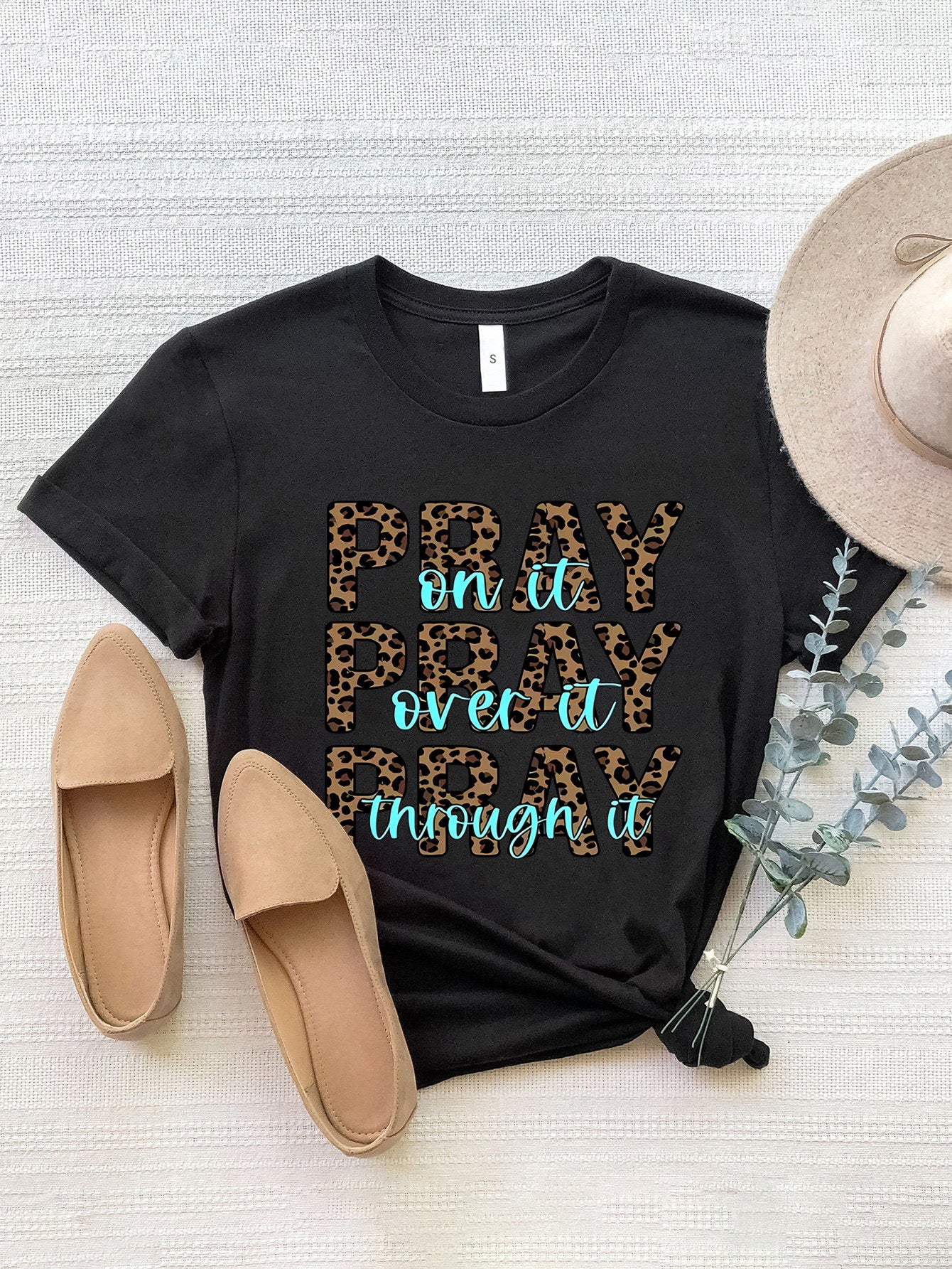 Black graphic tee with leopard print text "PRAY on it PRAY over it PRAY through it