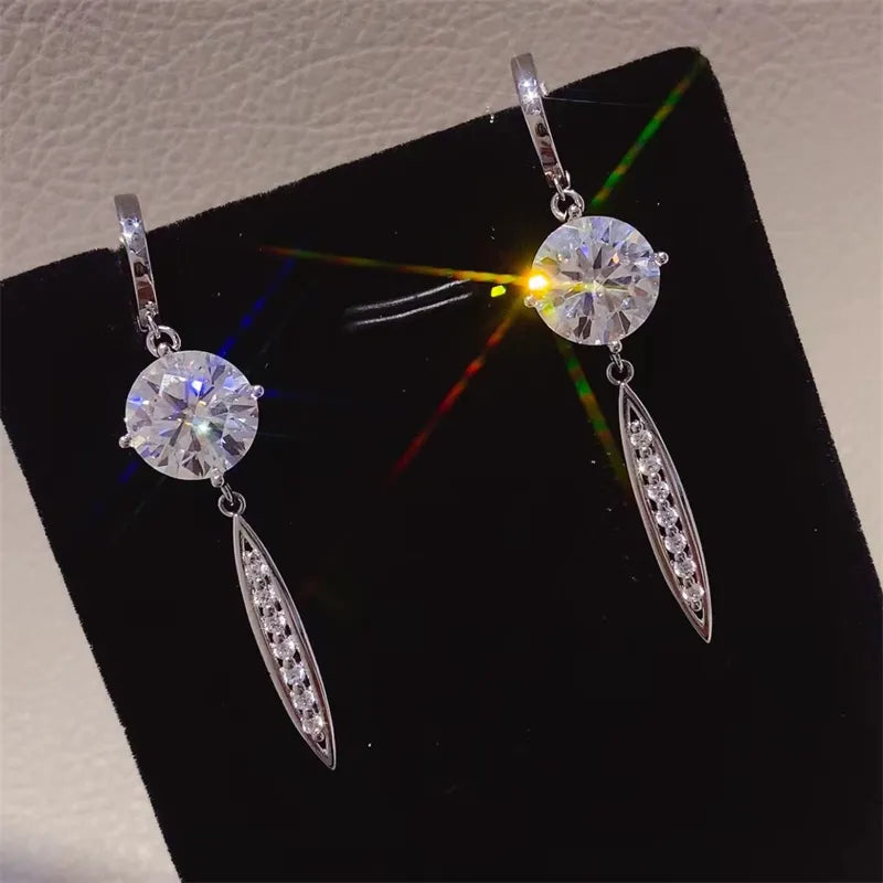 Silver moissanite orb dangle earrings with pavé accents on a black velvet display.