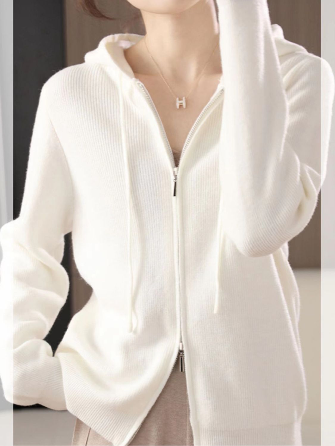 White ribbed knit zip-through hoodie with drawstring hood and silver zipper detail.