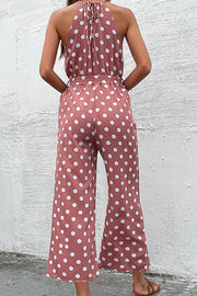 Red polka dot halter neck palazzo jumpsuit with tie back and belted waist.