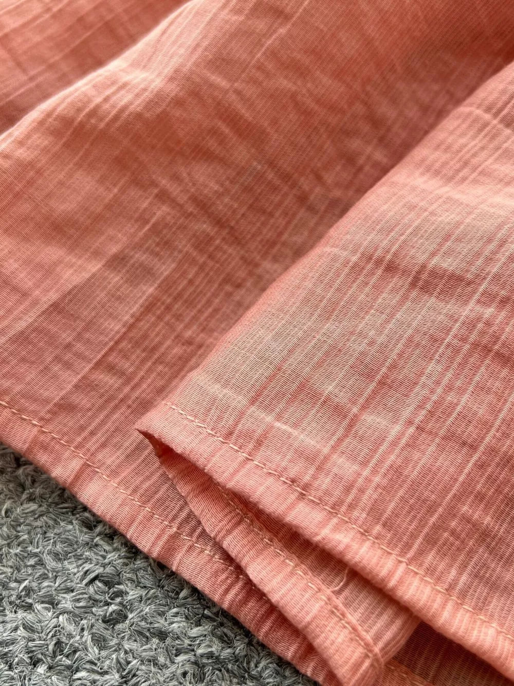 Textured tiered dress in Burnt Coral with subtle vertical stripes and visible stitching detail.