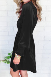 Black velvet mini dress with smocked bodice and long puff sleeves.