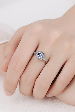 Silver halo cluster moissanite engagement ring with a round center stone and pavé band.