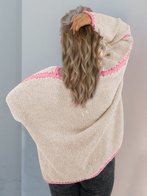 Oversized knit cardigan in tan with contrast pink stitching on shoulders, sleeves, and hem.