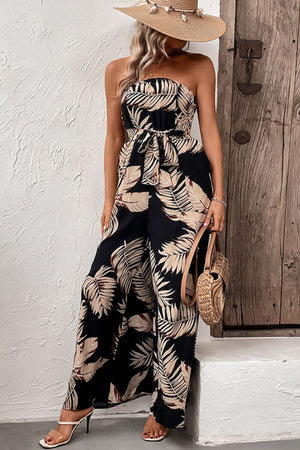 Black bandeau jumpsuit with tropical leaf print and tie waist, wide leg.