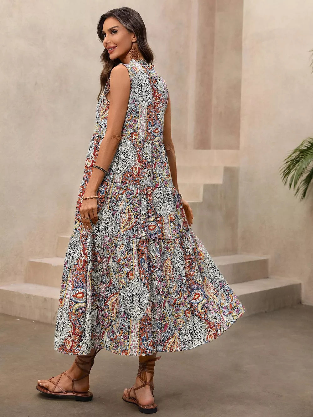 Paisley print midi dress with tie neck, tiered skirt, and decorative tassels.