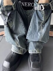 Distressed blue cotton wide-leg jeans with decorative straps and silver buckles.