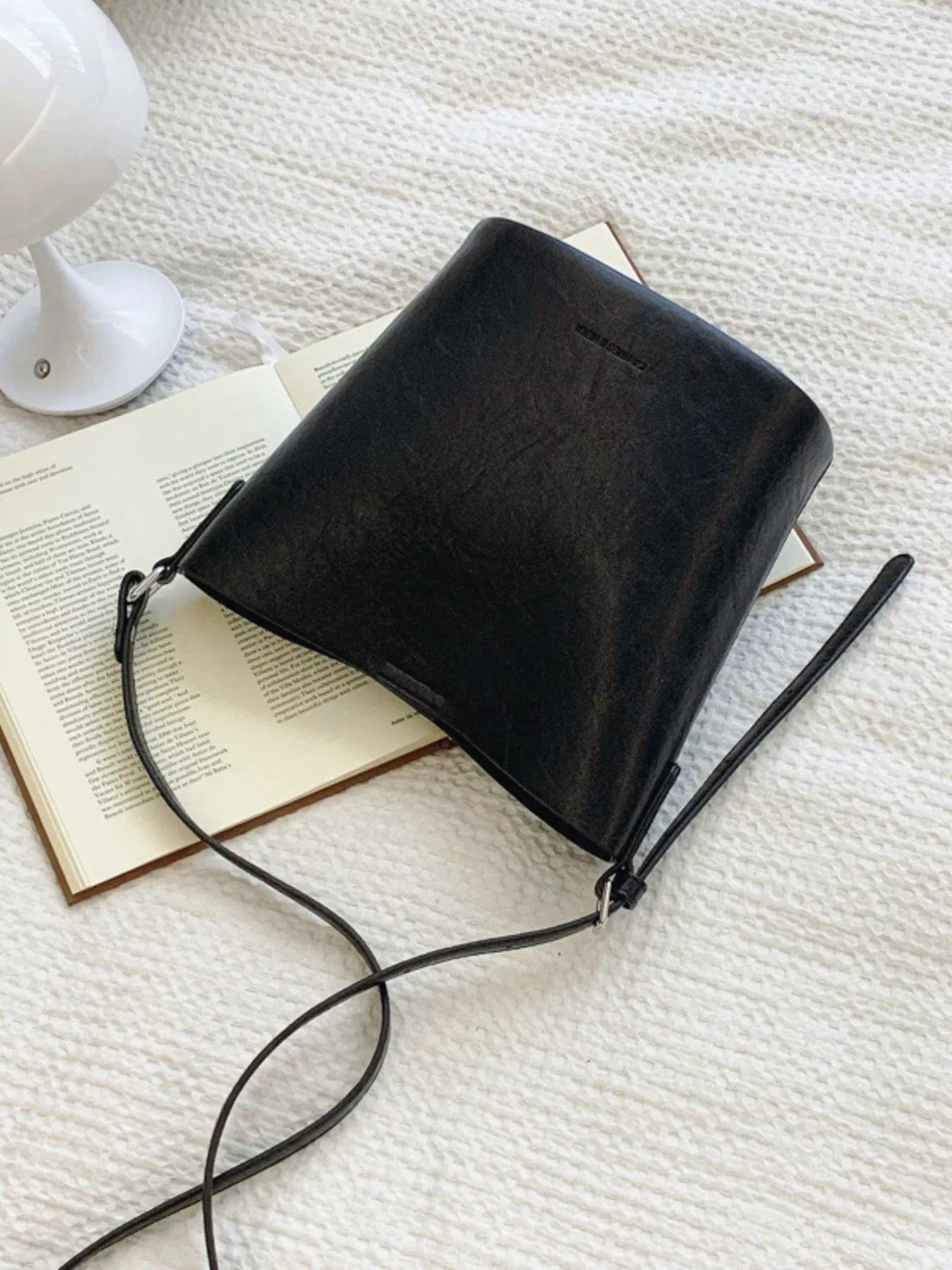 Sleek black leather bucket crossbody bag with adjustable strap