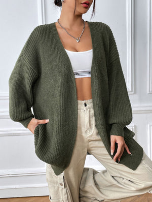 Olive green ribbed knit cardigan with balloon sleeves and open front, styled with a white crop top and beige cargo pants.