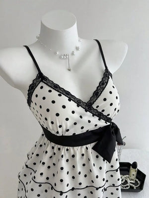 White polka dot camisole with black lace trim, black ribbon tie, and ruffled hem.