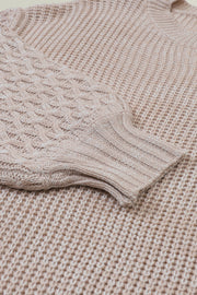 Tan knit sweater with diamond textured sleeves and ribbed cuffs.