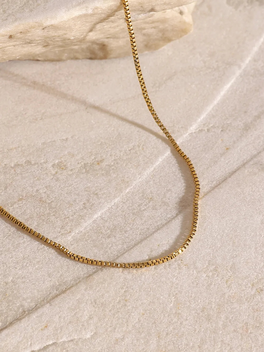 Gold layered necklace with serpentine and cross pendants, adjustable length.