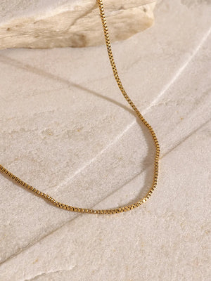 Gold layered necklace with serpentine and cross pendants, adjustable length.