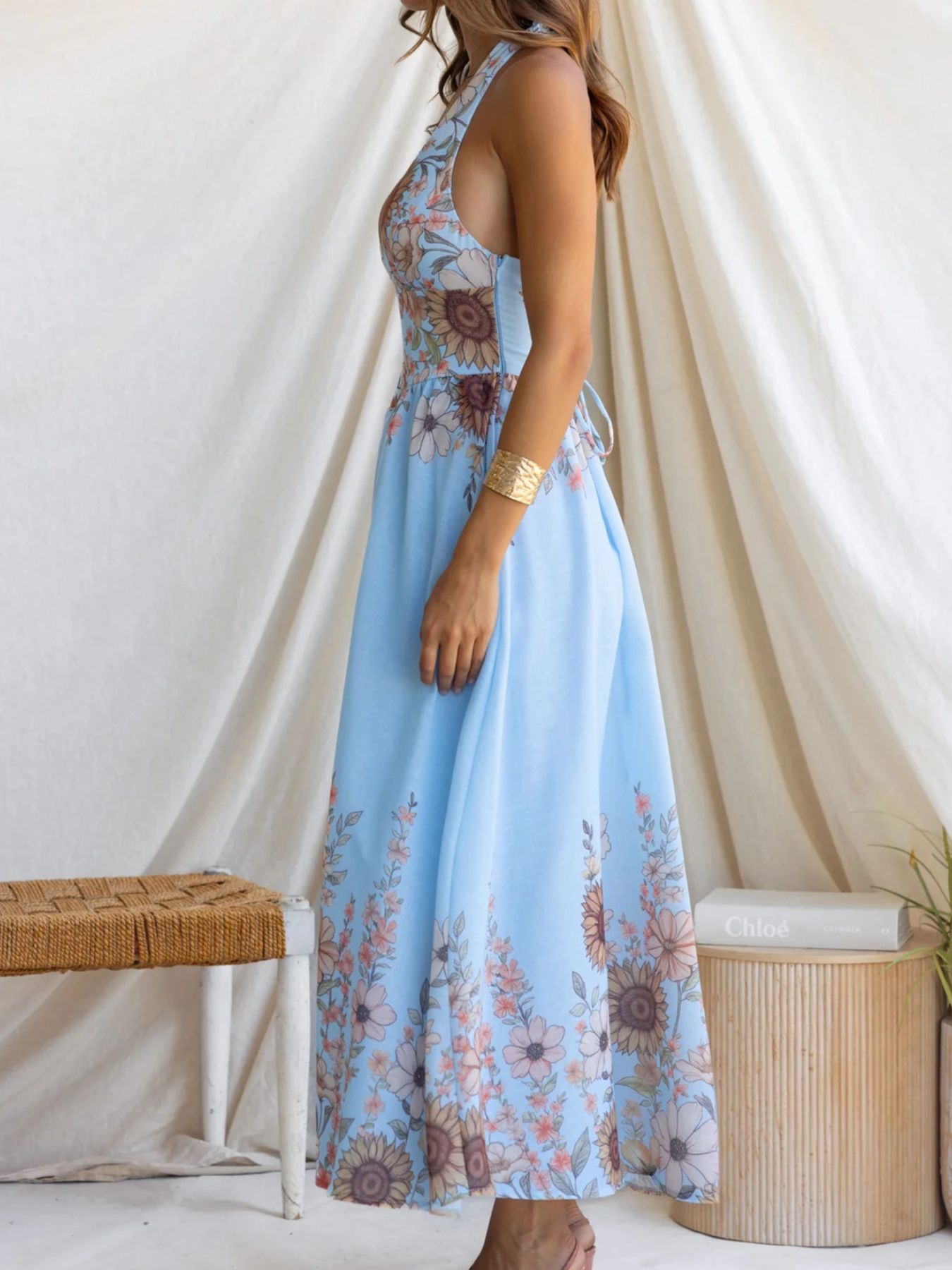 Blue floral halter neck maxi dress with a cinched waist and tie back detail.