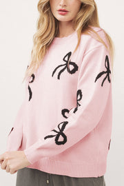 Blush pink knit crewneck sweater with allover black bow motifs.