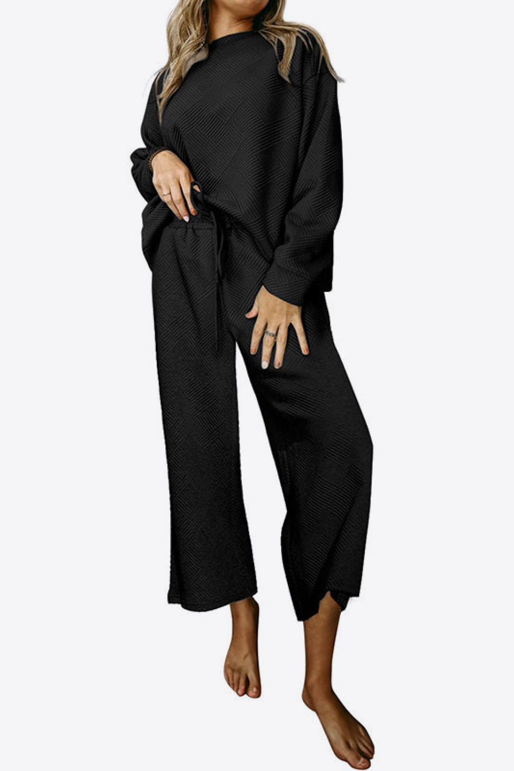 Black loungewear set with textured pattern, crew neck top and wide leg pants.