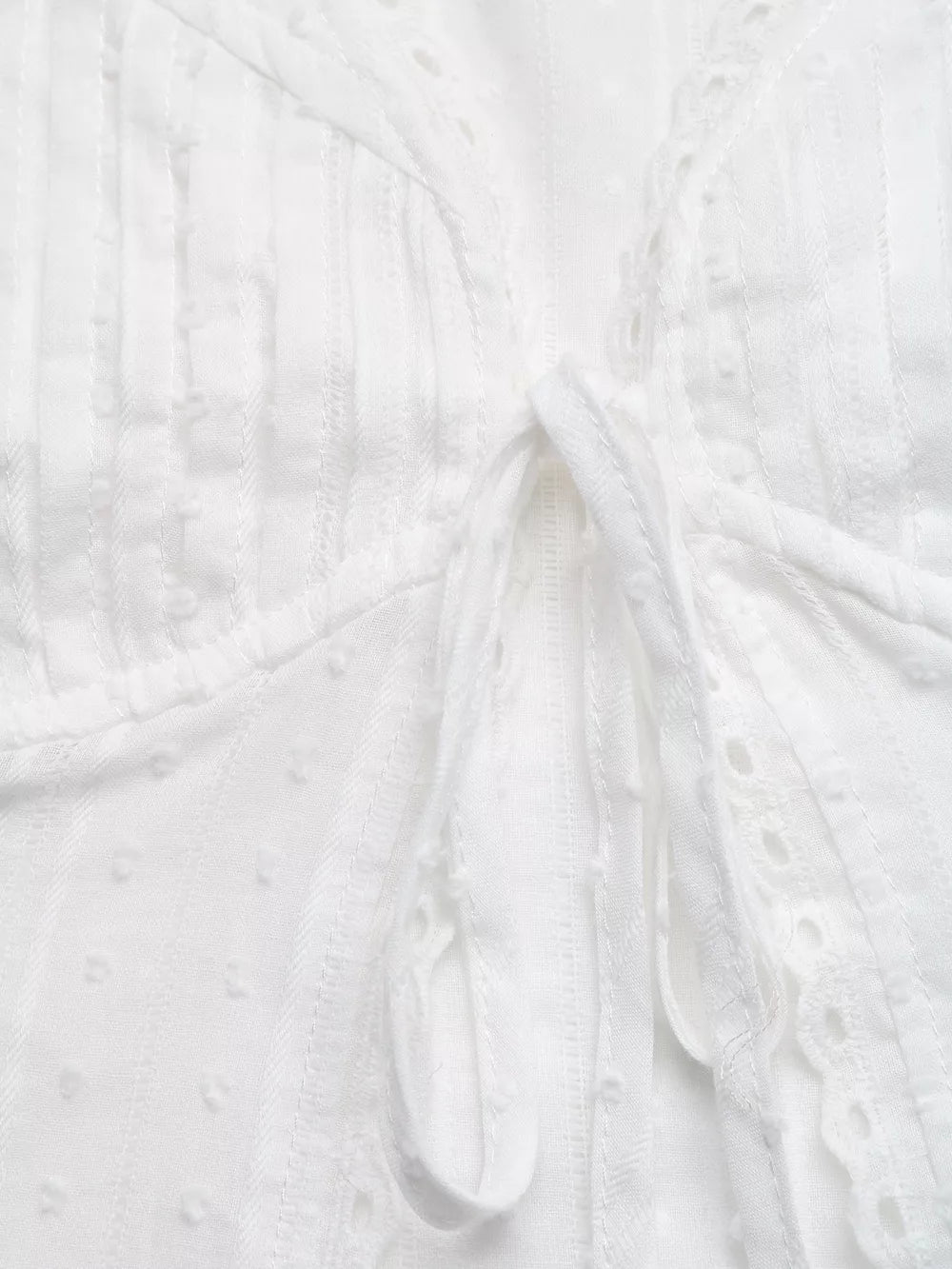 White lace-trimmed tie-front maternity blouse with textured fabric and eyelet details.