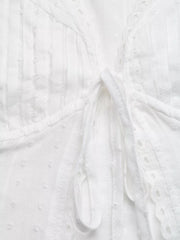 White lace-trimmed tie-front maternity blouse with textured fabric and eyelet details.