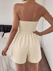 Cream pleated V-neck strapless romper with smocked bodice and loose shorts.