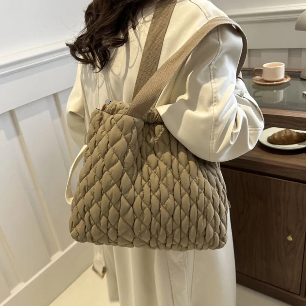 Khaki quilted drawstring carryall bag with textured pattern and canvas straps.