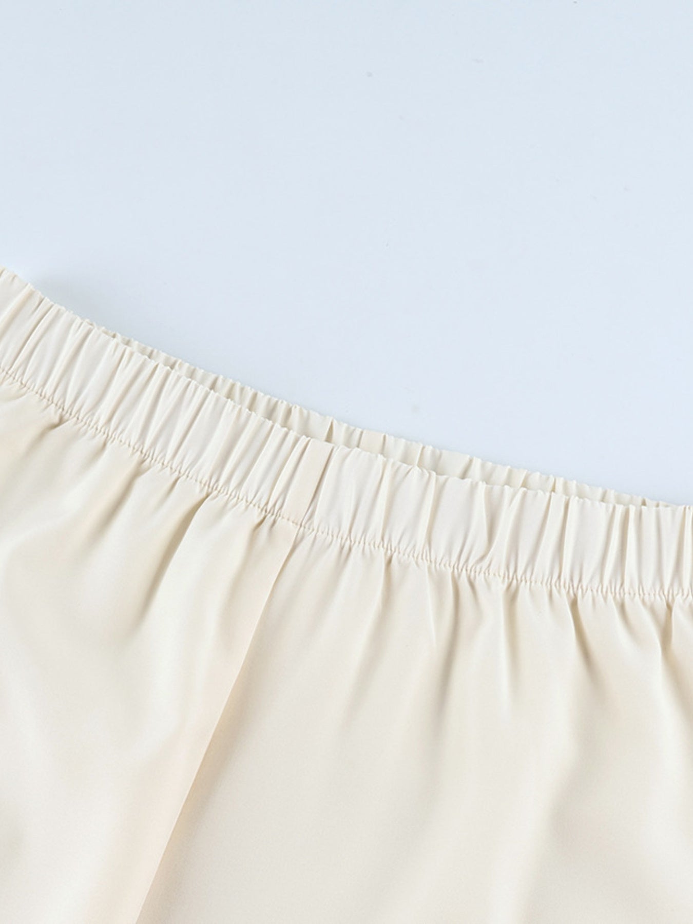 Cream lounge set pants with elastic waistband and black piping detail.
