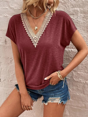 Burgundy dolman sleeve top with lace trim V-neck, paired with distressed denim shorts.
