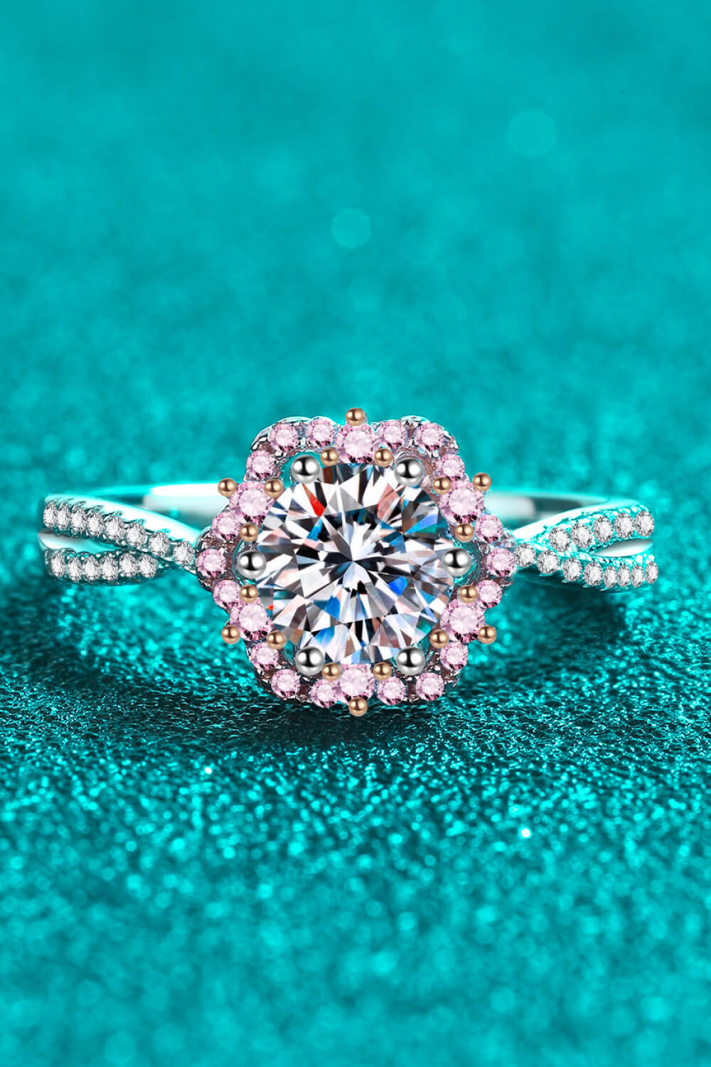 Silver moissanite ring with a floral halo of pink stones and a split band.