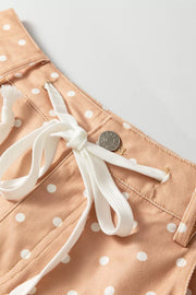 Peach polka dot maternity trousers with white drawstring and button detail.