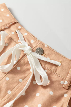 Peach polka dot maternity trousers with white drawstring and button detail.