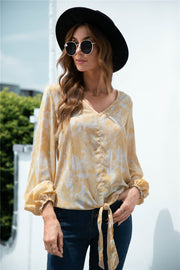 Light yellow swirl print blouse with V-neck, balloon sleeves, and tie-front detail.