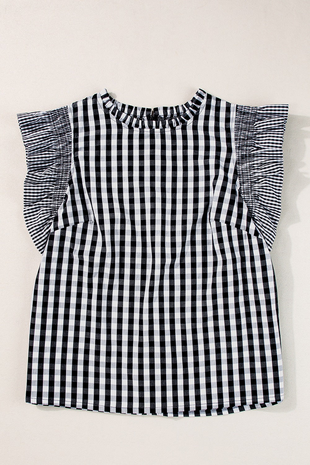 Black gingham blouse with ruffled cap sleeves and a mock neckline.