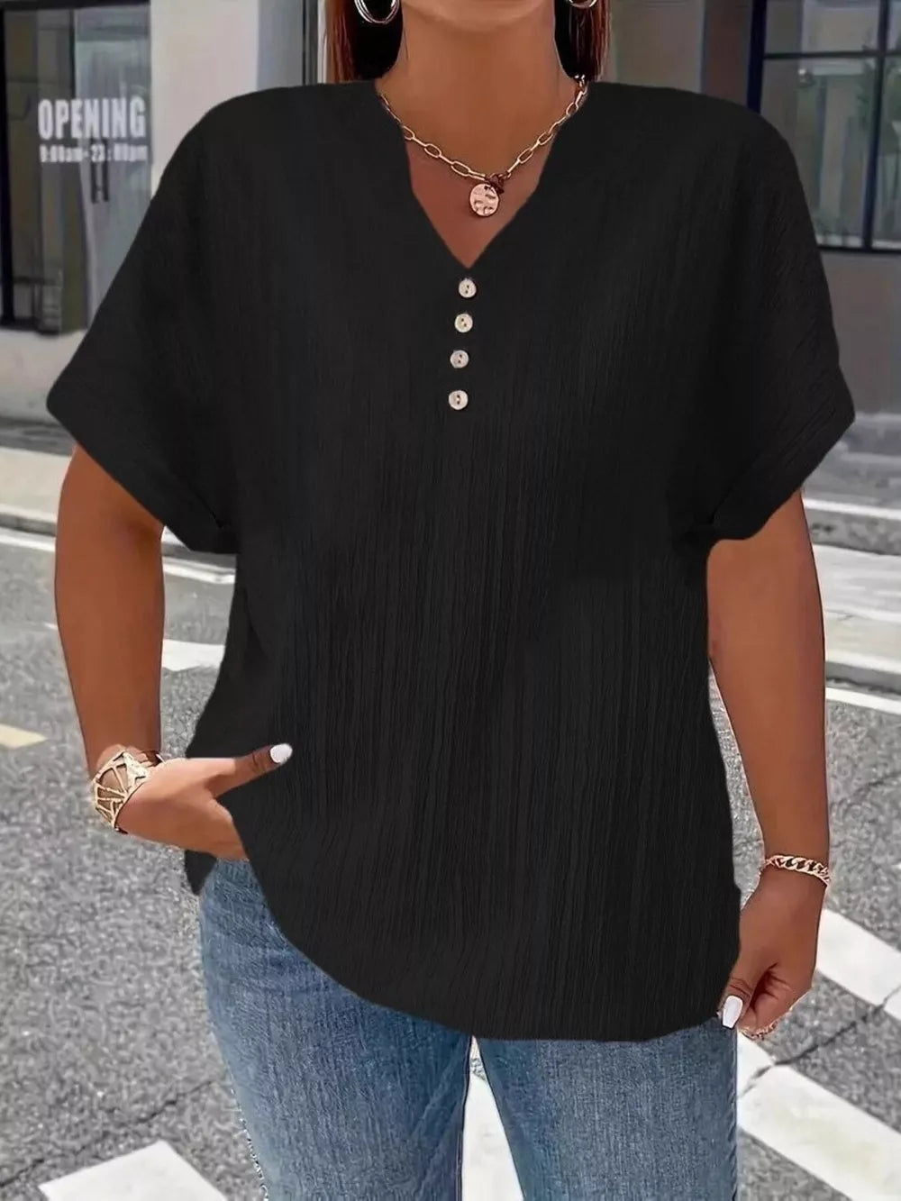 Black textured V-neck t-shirt with decorative buttons and short sleeves.
