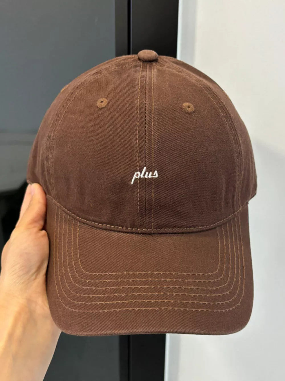 Brown baseball cap with white embroidered "plus" detail.