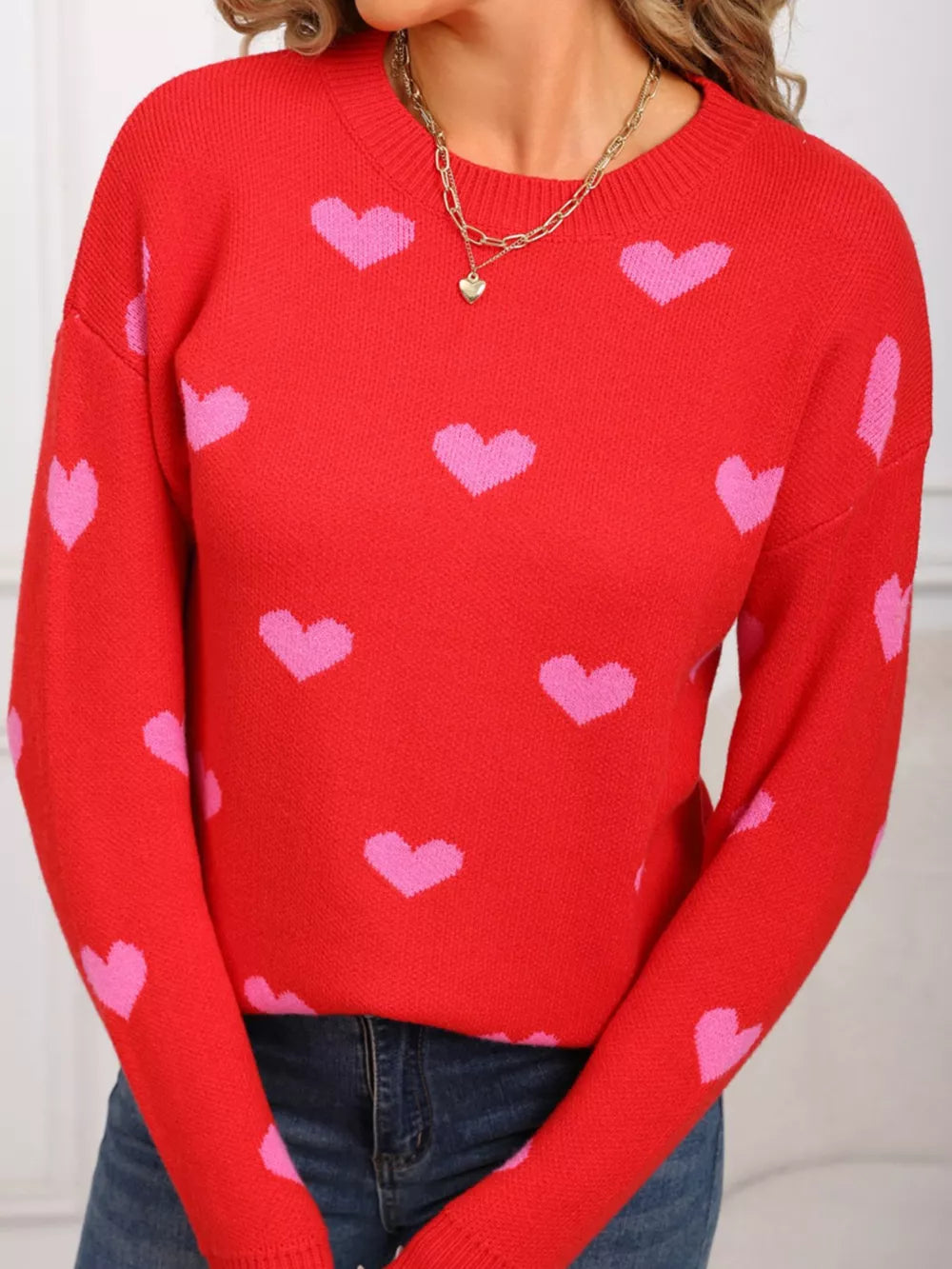 Red acrylic sweater with pink heart print and crew neck.