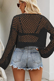 Black cropped open knit top with bell sleeves and a relaxed fit, styled with denim shorts.