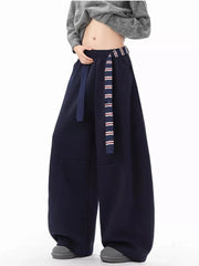 Navy blue men's wide-leg sweatpants with a striped belt and grey sneakers.