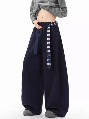 Navy blue men's wide-leg sweatpants with a striped belt and grey sneakers.