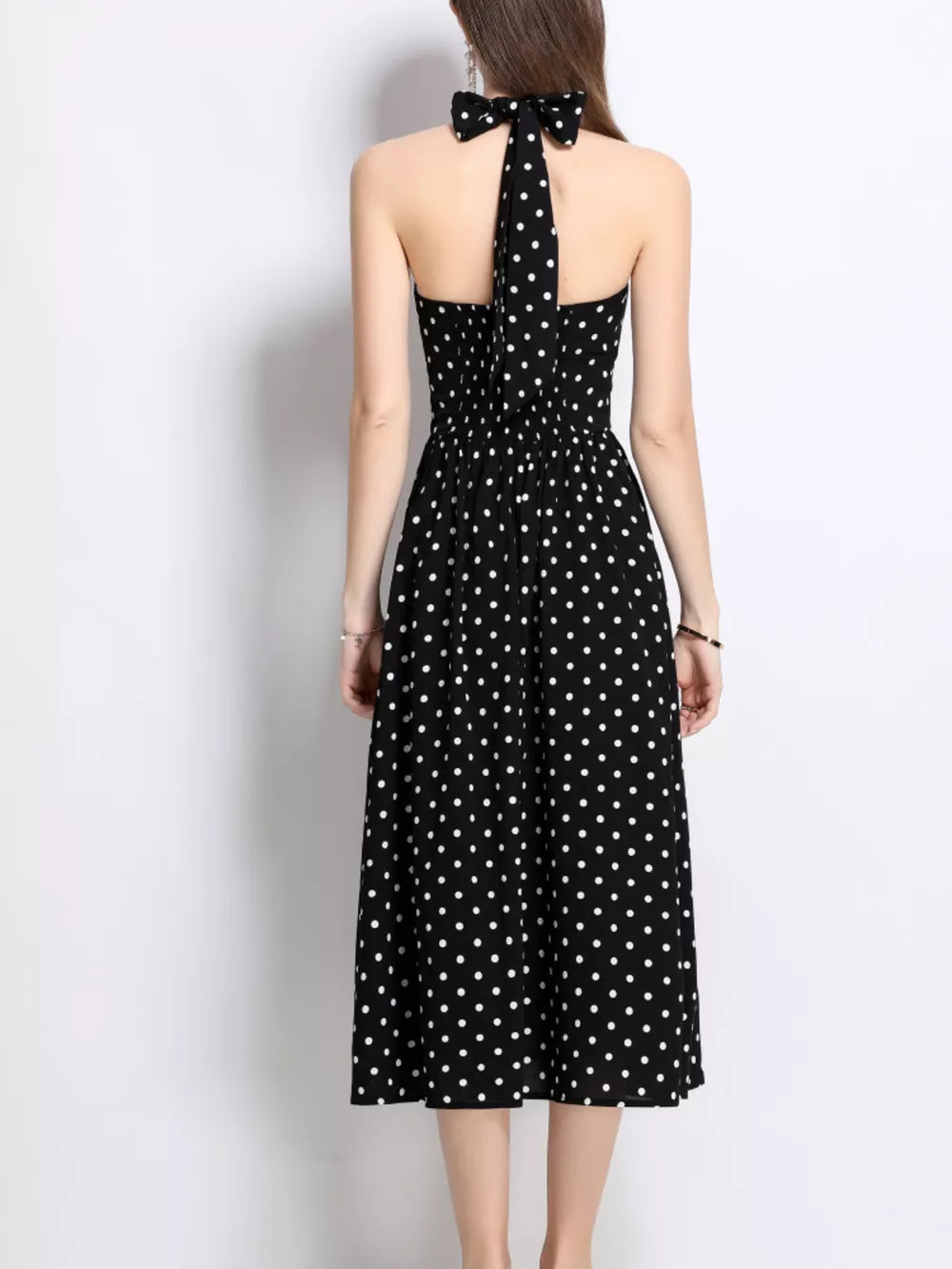 Black polka dot halter midi dress with a bow detail at the neck.