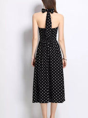 Black polka dot halter midi dress with a bow detail at the neck.