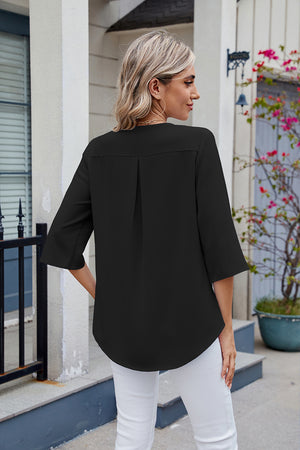 Black V-neck flutter sleeve blouse with back pleat detail and curved hem.