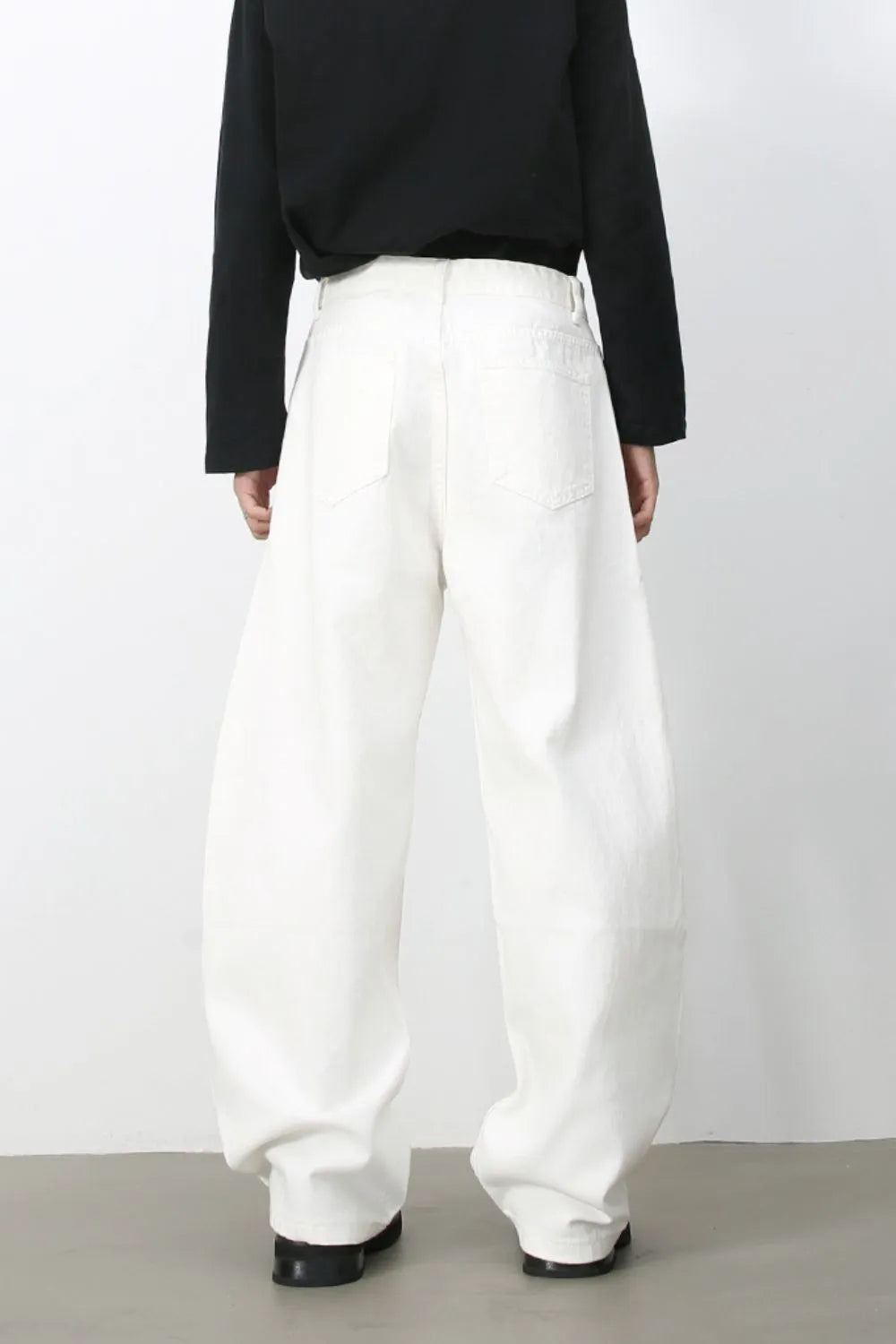 Sculpted white denim balloon trousers with a high waist and wide leg, shown from the back.