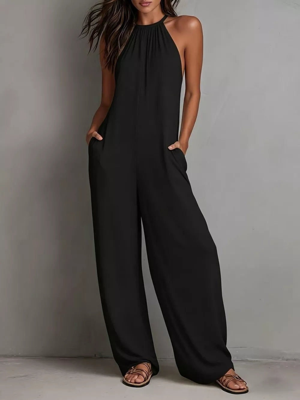 Black halter neck wide leg romper with pockets, styled with sandals.