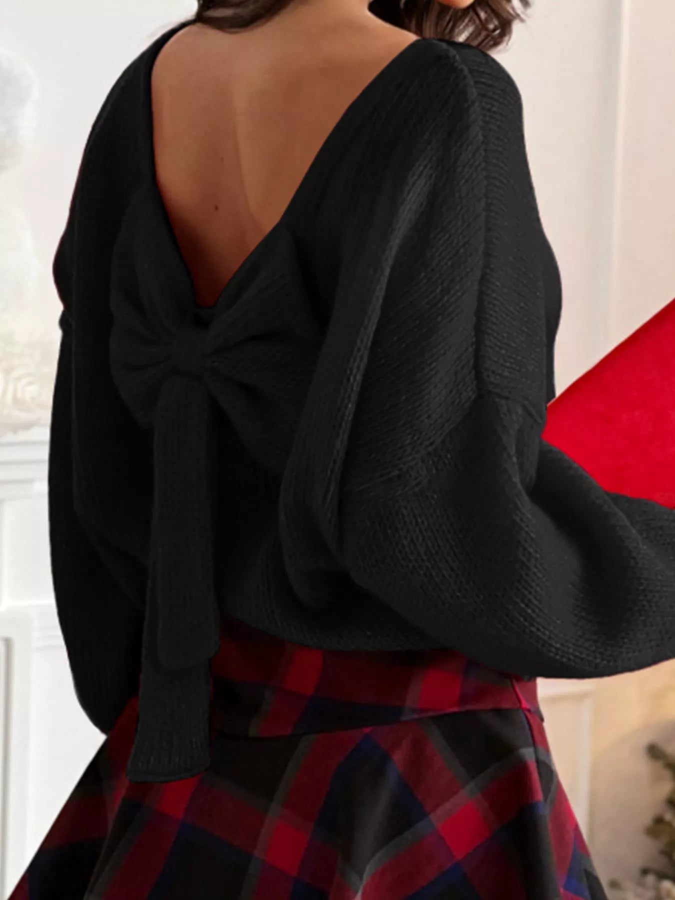 Black long-sleeve sweater with a V-back and a large bow detail.