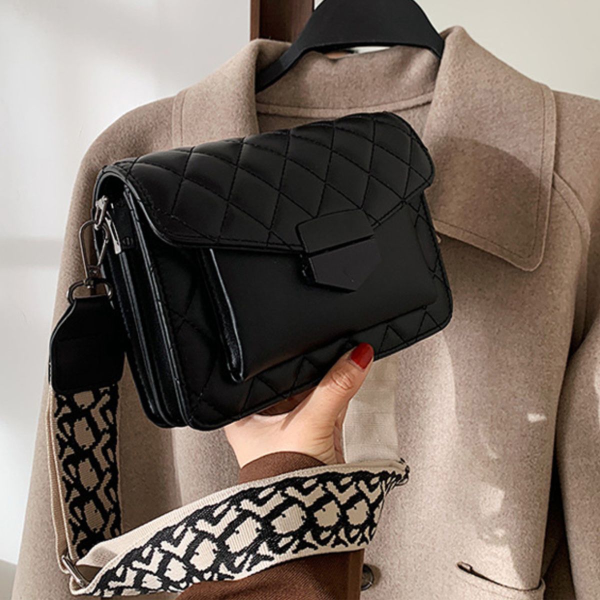 Chic quilted black flap crossbody bag with patterned strap and gold hardware detail.