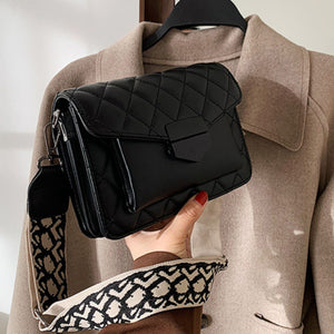 Chic quilted black flap crossbody bag with patterned strap and gold hardware detail.