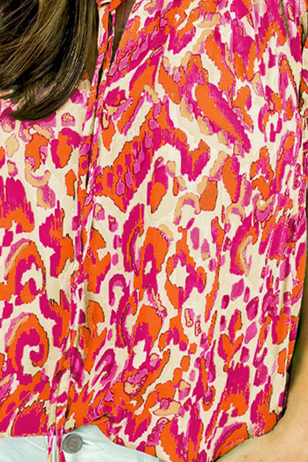 Printed cap-sleeve blouse with abstract pattern in pink and orange on cream.