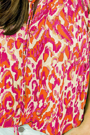 Printed cap-sleeve blouse with abstract pattern in pink and orange on cream.