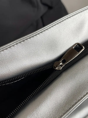 Silver metallic tote bag detail with zipper and black interior.