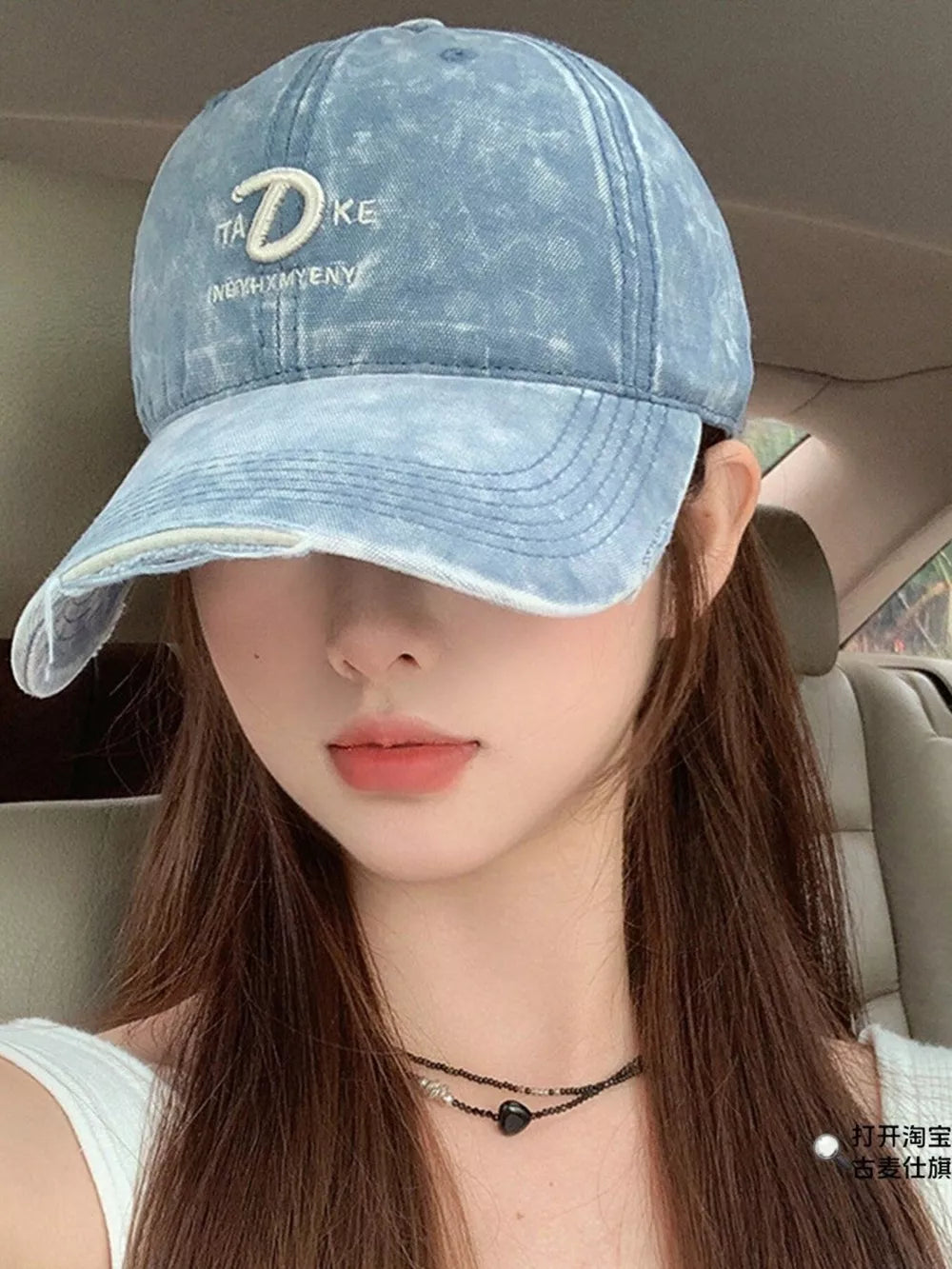 Blue denim baseball cap with embroidered D and text detail, distressed brim.